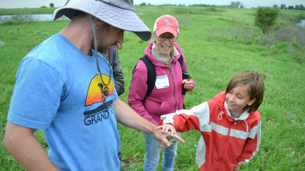Girl petting a frog that a man is holding