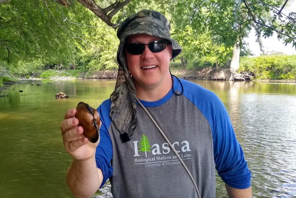 Troy Goodnough standing in the Lac qui Parle River with a Mussel