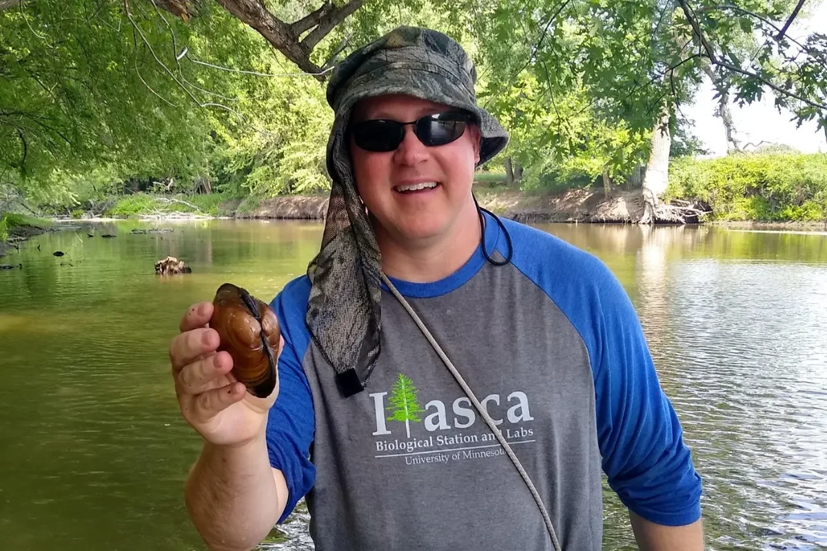Troy Goodnough standing in the Lac qui Parle River with a Mussel