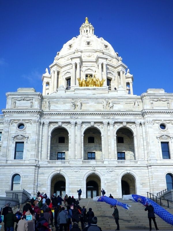 The Minnesota State Capitol and people marching up its steps.
