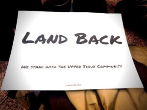 A "Land Back - We stand with the Upper Sioux Community" sign that supporters of the land transfer used to show solidarity with the Upper Sioux Community at the meeting.