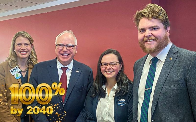A photo of CURE staff and MN Gov. Tim Walz celebrating at the signing of the 100% Clean Energy Act in February. Text in lower left hand corner: "100% by 2040"