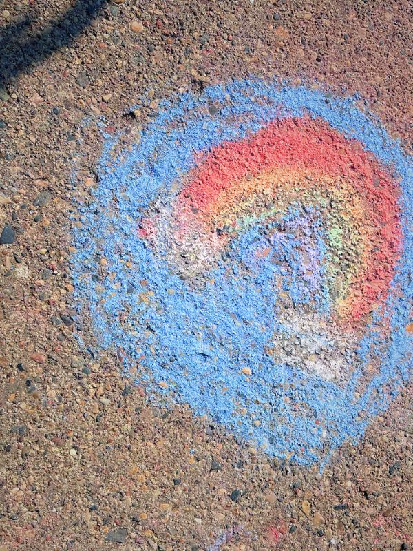A child's chalk drawing of a rainbow on a sidewalk