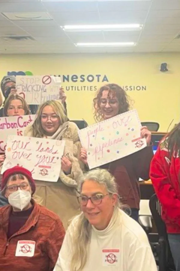 students holding up anti-co2 pipeline signs at a MN PUC hearing on the subject on Dec 12