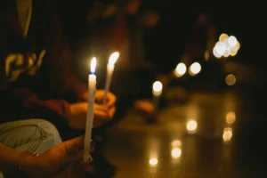 hands holding candlesticks at a candlelight vigil