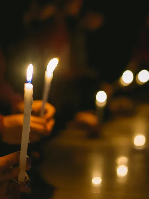 two hands holding candles at a candlelight vigil