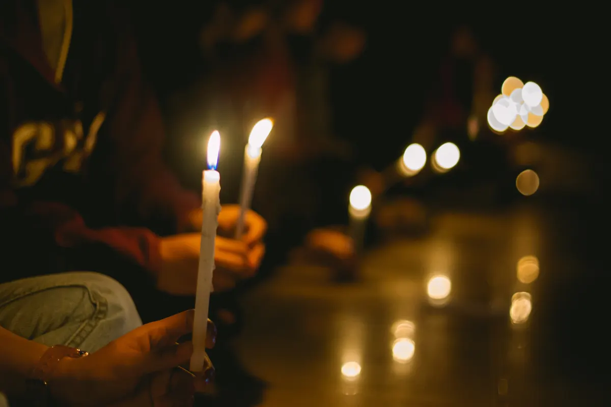 hands holding candlesticks at a candlelight vigil