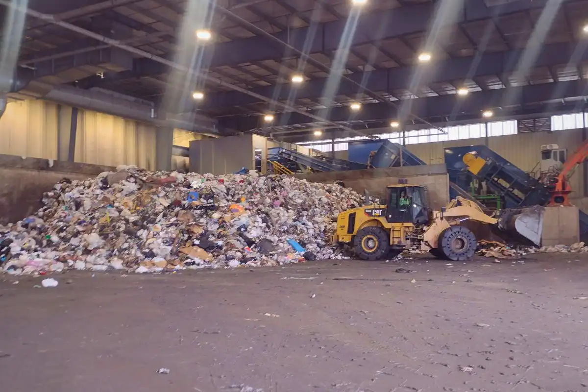 A front loader adding to a massive pile of waste.