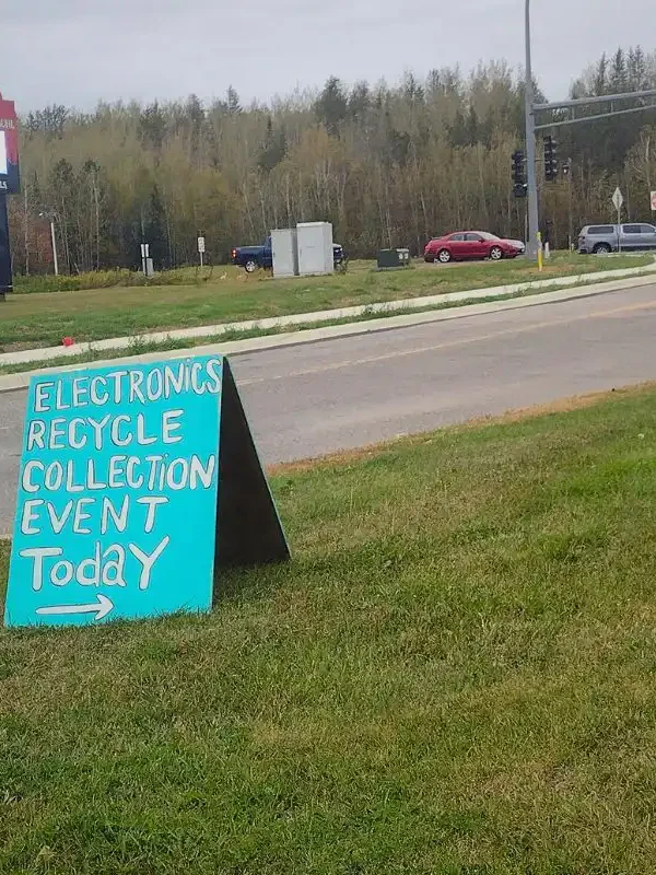 A teal green sign announcing a waste collection event