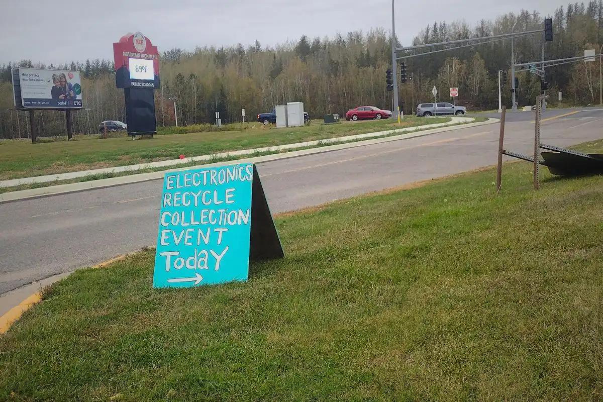 A teal green sign announcing a waste collection event