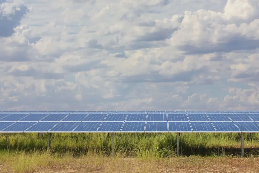 solar panels in a grassy field with clouds in the sky above