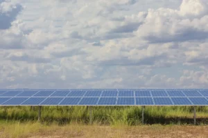 solar panels in a grassy field with clouds in the sky above