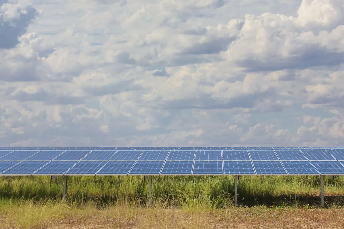 solar panels in a grassy field with clouds in the sky above